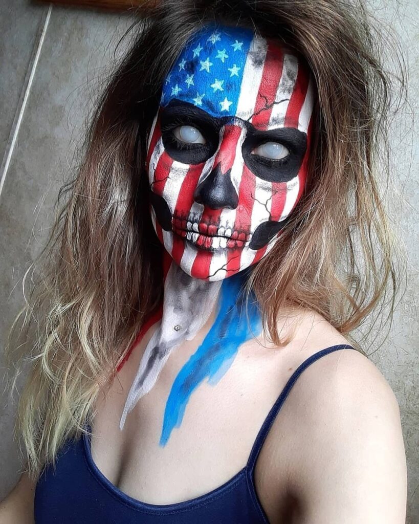 Woman with skull face paint featuring the American flag pattern and white eyes.
