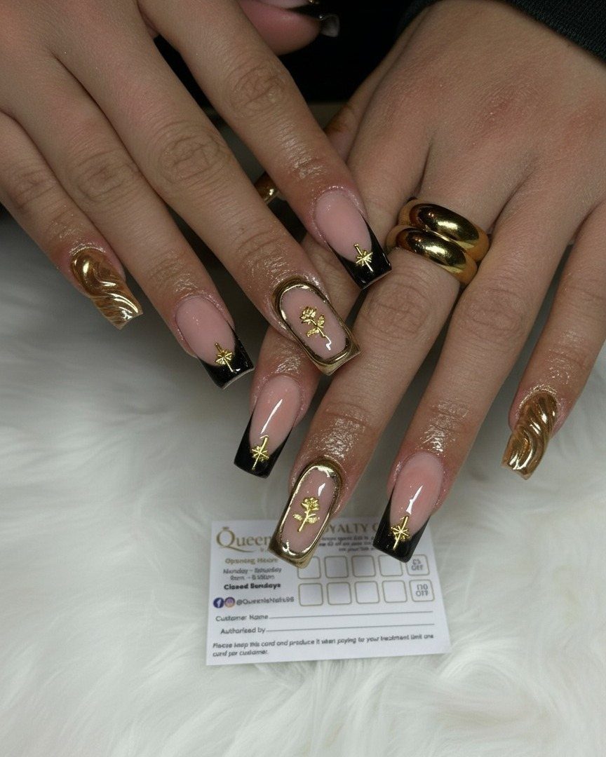 Long coffin nails with black French tips, gold stars, and 3D gold accents.