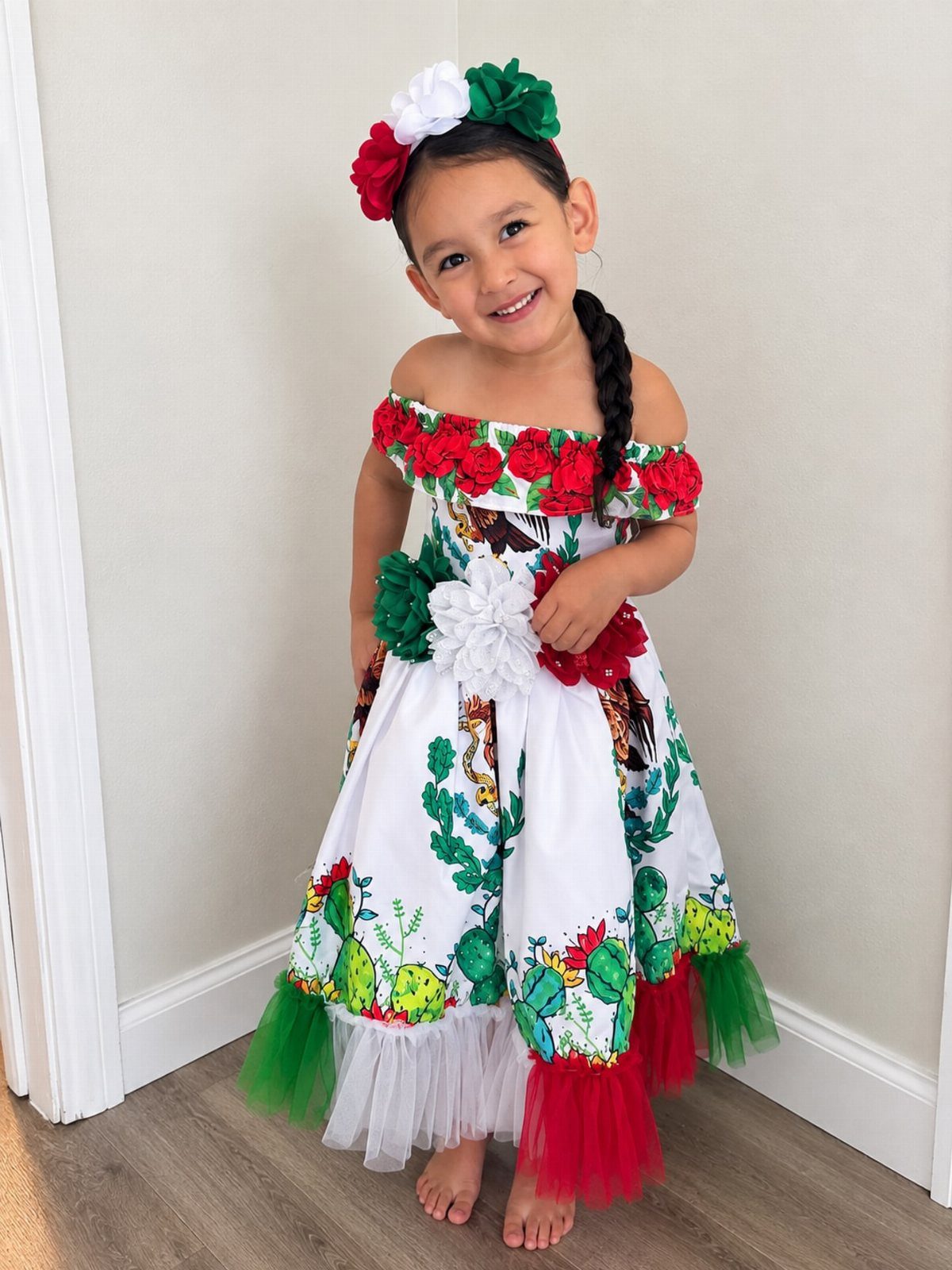 Young girl wearing a white dress with cactus prints and red floral accents.