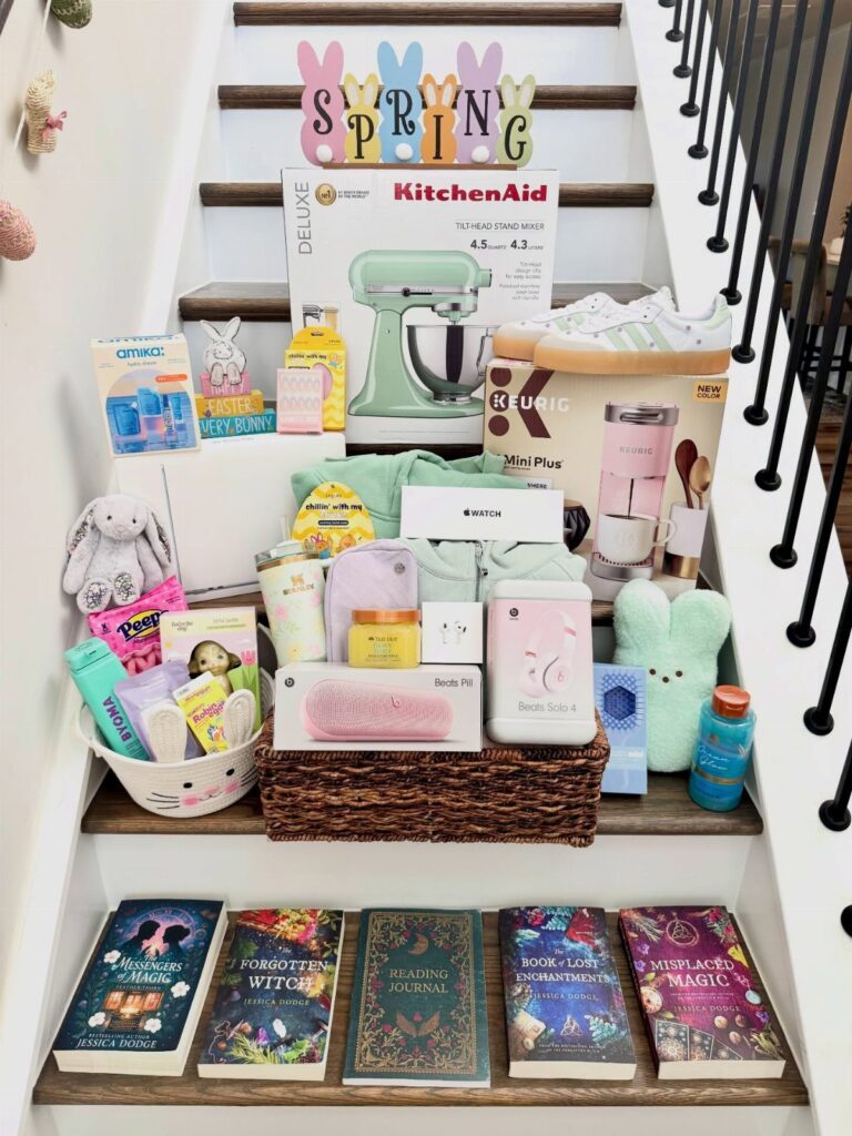 Assorted adult Easter gifts including a mixer and books arranged on white stairs.