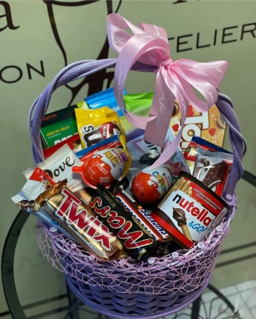 Purple basket filled with assorted chocolate candies and topped with a pink bow.
