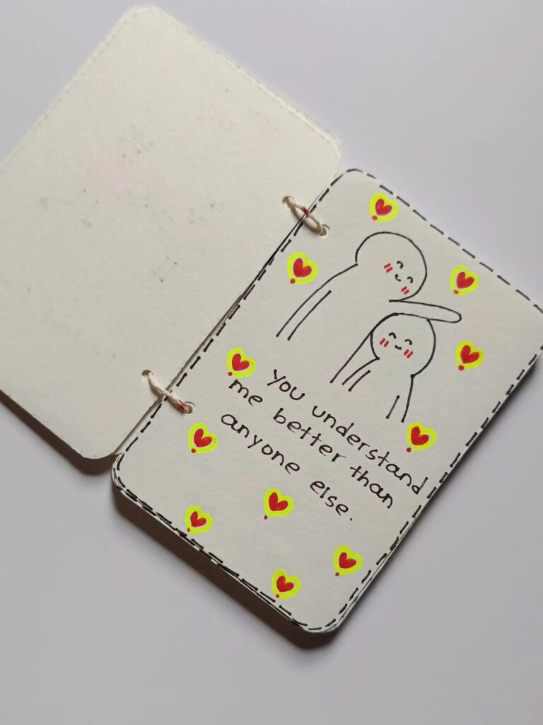 Handmade card with a drawing of two figures hugging and a heartfelt message.