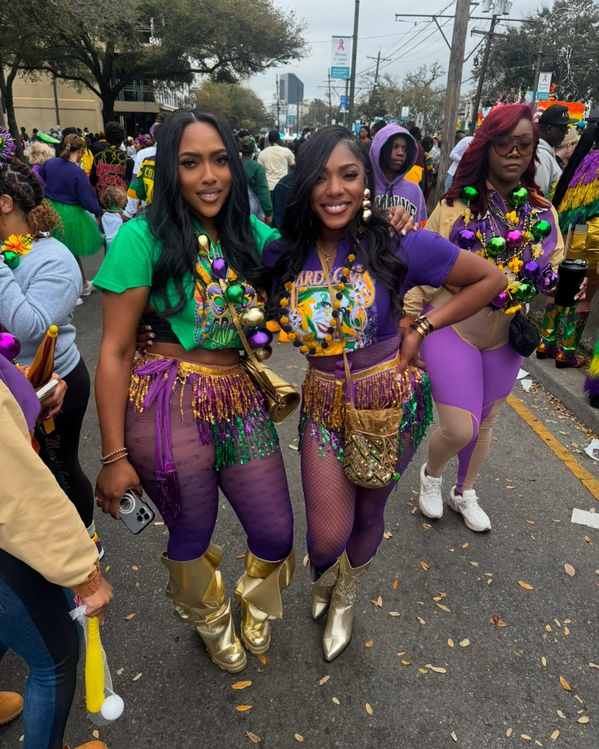 Three women wearing purple, green, and gold Mardi Gras costumes on a city street.