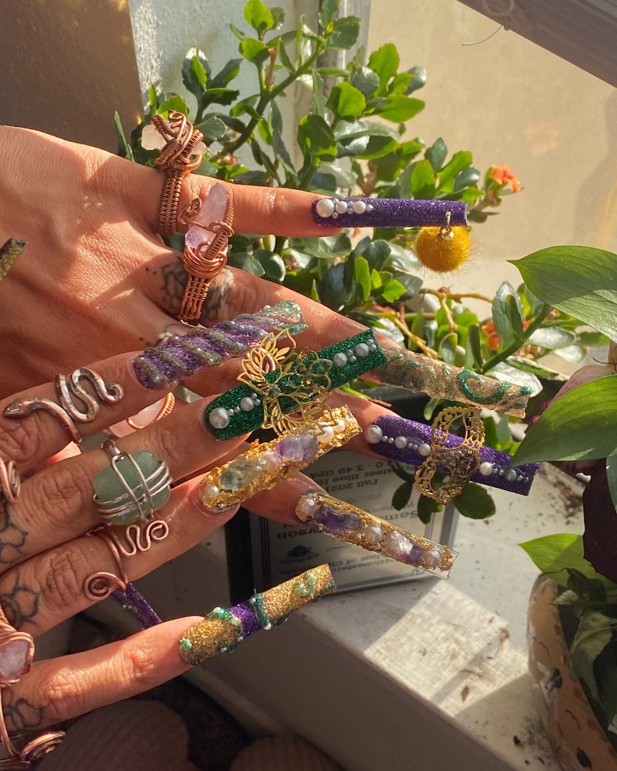 Ornate purple, gold, and green Mardi Gras nail art with pearls and charms.