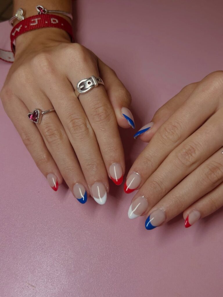 Short nails with red, white, and blue French tips on a pink background