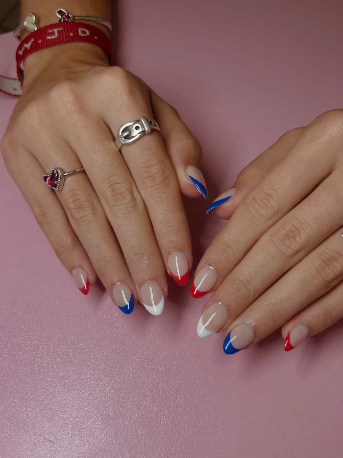 Short nails with red, white, and blue French tips on a pink background