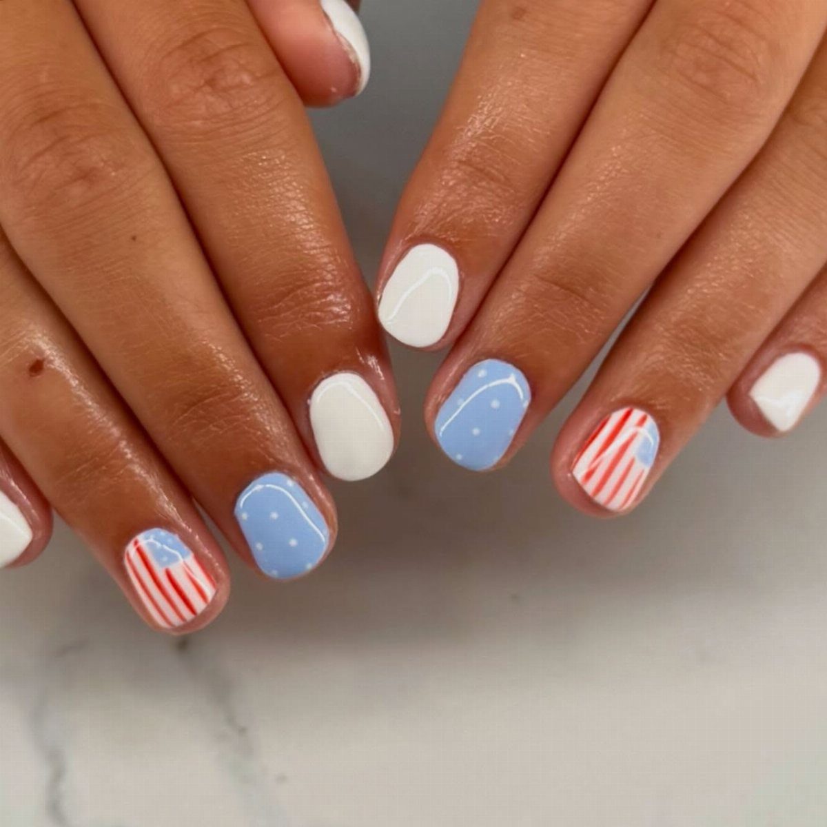 Manicured nails with red, white, and blue 4th of July themed nail art.