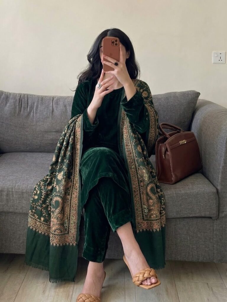 Person in a dark green velvet suit with gold embroidered shawl sitting on sofa