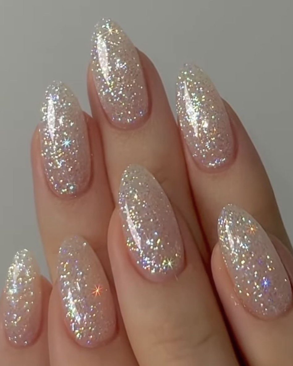 Almond-shaped nails with shimmering holographic silver glitter polish on a light background