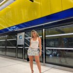 Woman in a silver sequined miniskirt and white tank top at a subway station