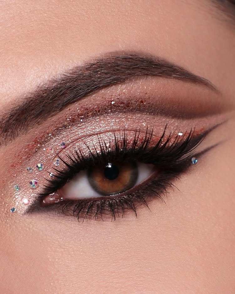 Eye with shimmering rose gold makeup and sparkling rhinestones for a festive look