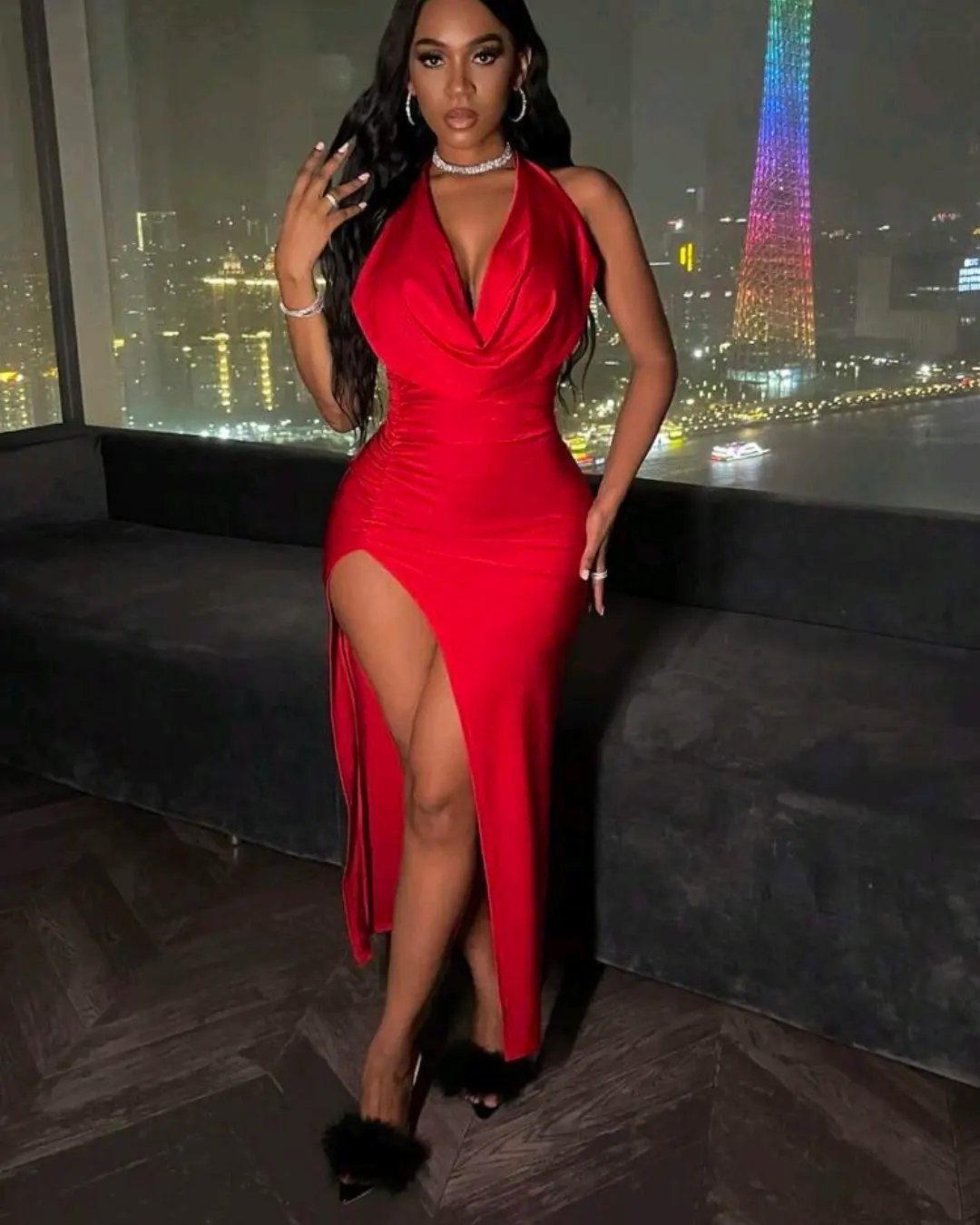 Woman in a red satin halter neck maxi dress with a high front split.