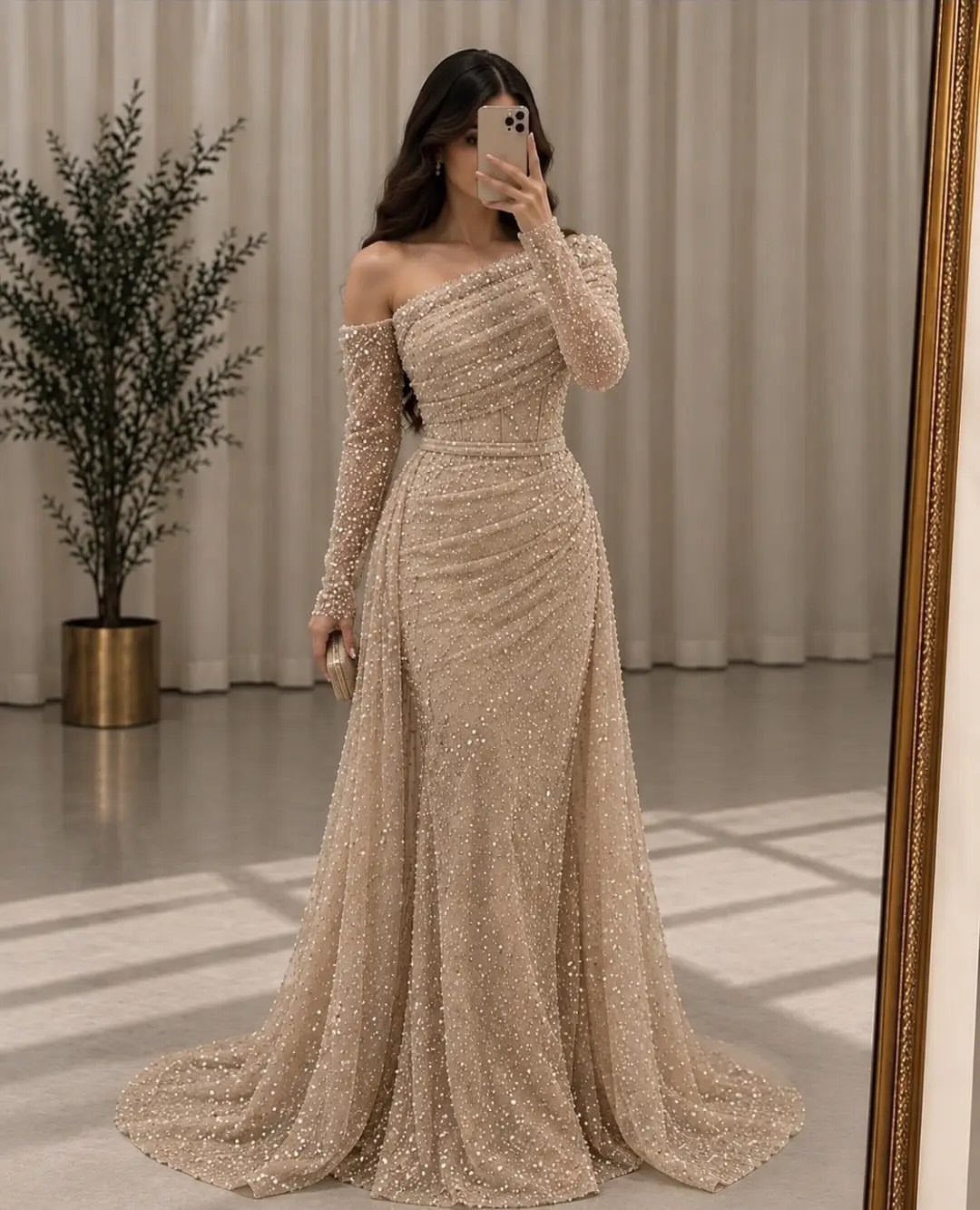 Woman in a gold sequined floor-length gown posing for a mirror selfie.