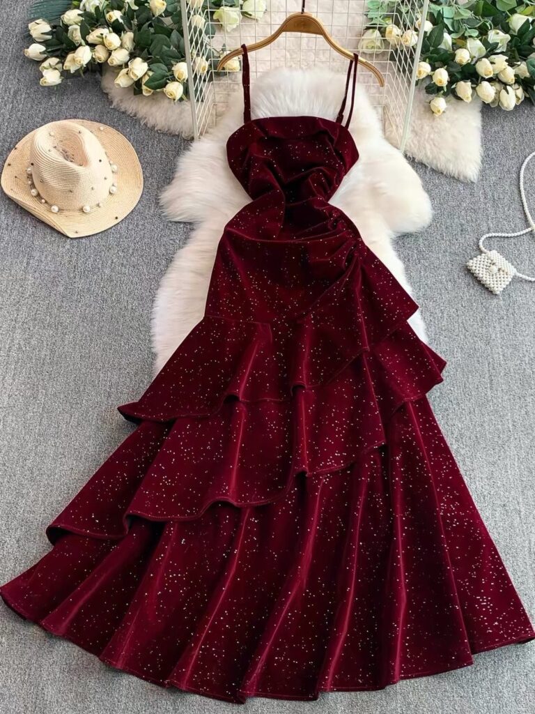 Burgundy velvet tiered maxi dress with glitter accents hanging over white faux fur.