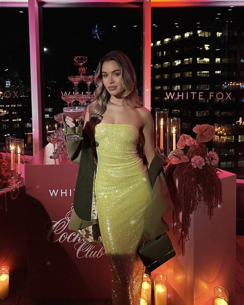 Woman in a shimmering yellow mini dress and gold boots at a city event.