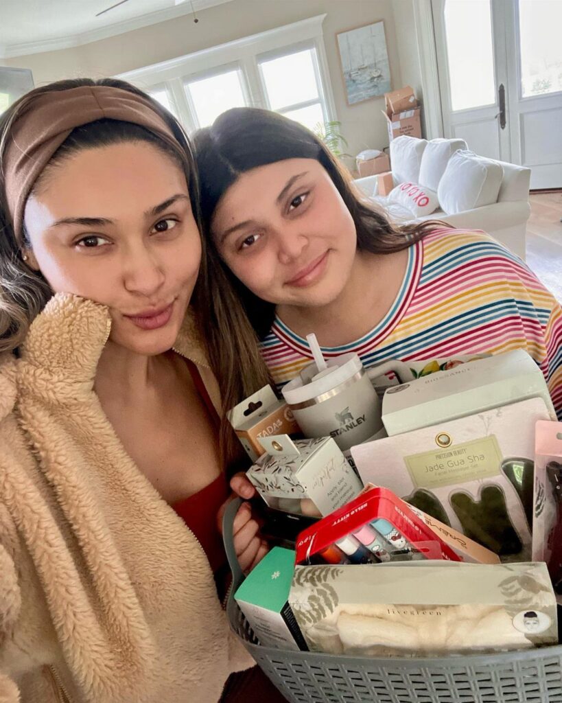 Two women posing with a grey basket filled with non-candy Easter gifts.
