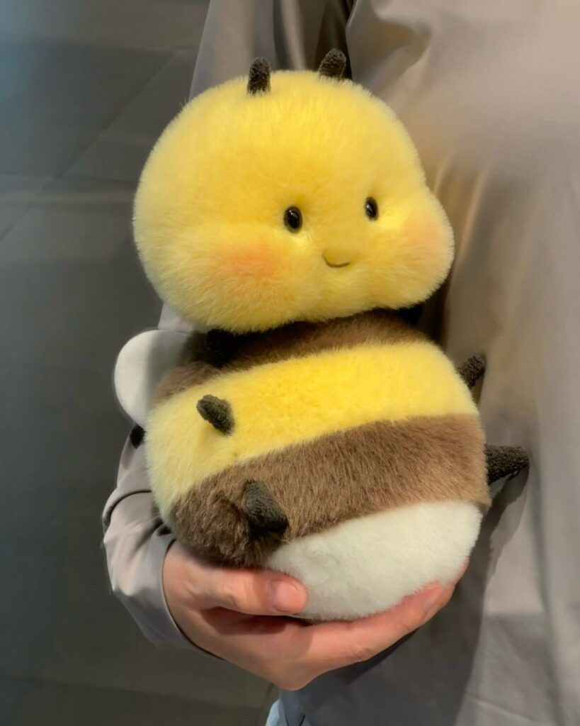 Small plush bumblebee toy with yellow and brown stripes held in a hand.