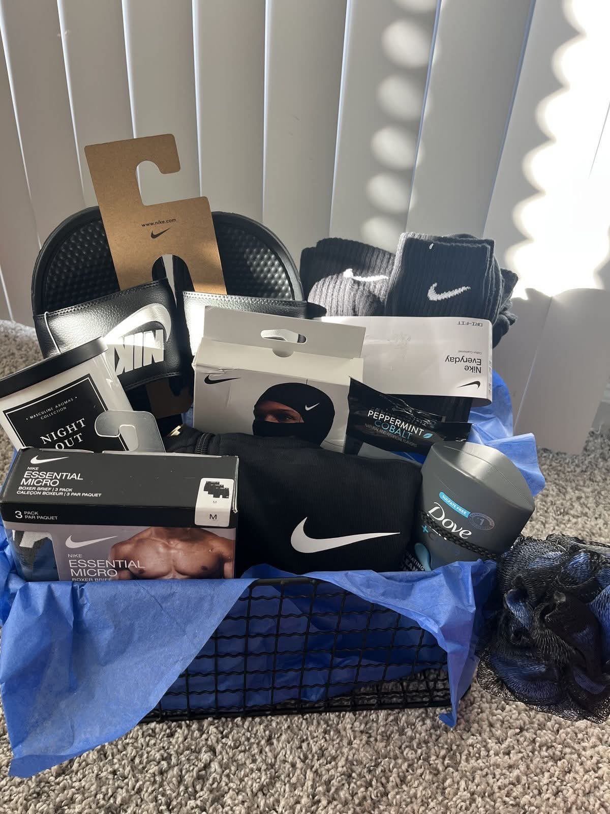 Gift basket for men containing Nike apparel, footwear, and grooming products in blue tissue.