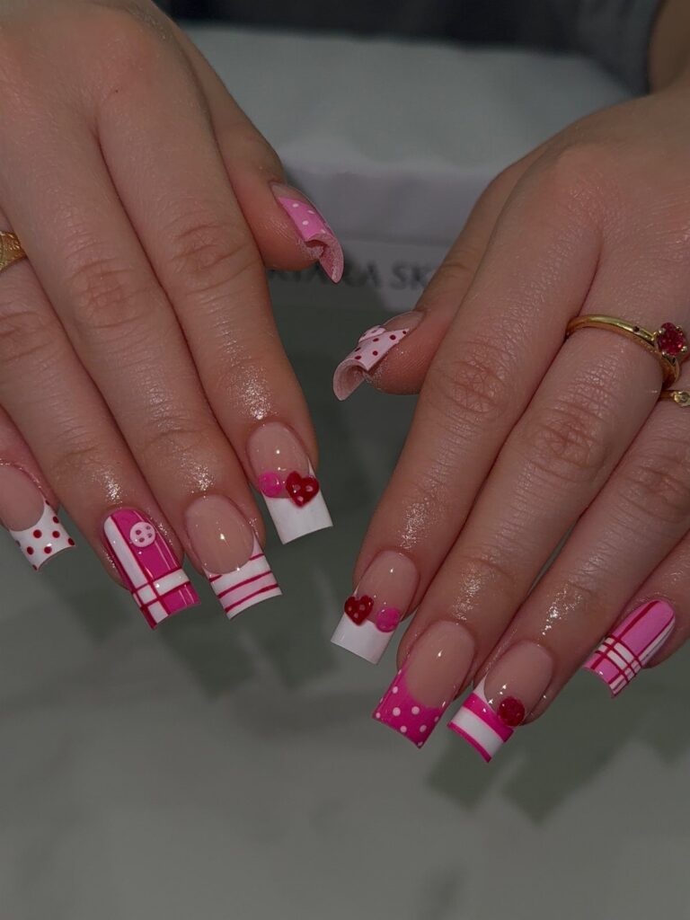 Square acrylic nails with pink and white patterns and red hearts for Valentine's Day.